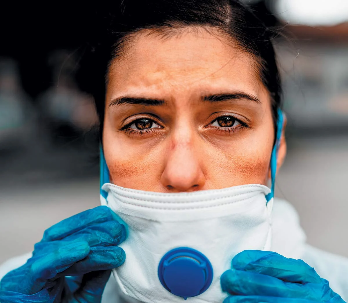 A nurse wearing protective equipment and a respirator mask