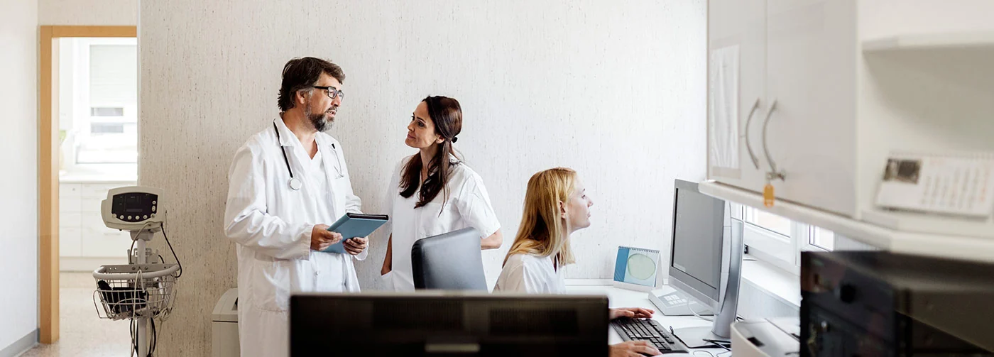 Clinicians discussing work at a nurses station